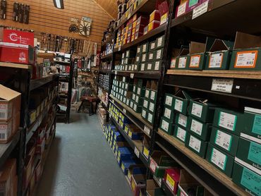 A narrow aisle in a hardware store with shelves packed with boxes and tools.