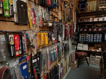 A shop aisle filled with various tools and accessories hanging on the wall and shelves.