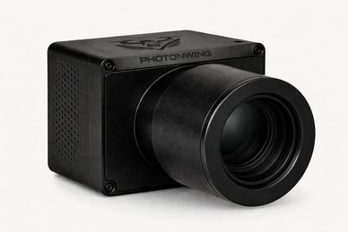 Black Photonwing camera with large lens on white background.