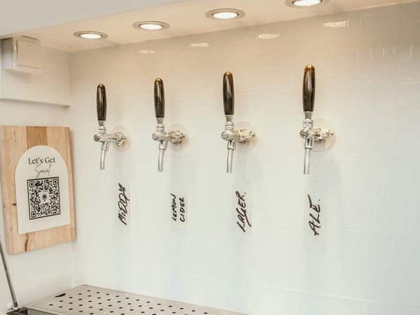 Four beer taps labeled with different drinks and glasses below.