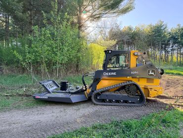 John Deere 325G tracked skid steer in a forest clearing.