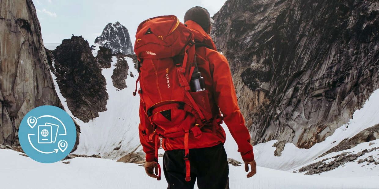 Hiker in red jacket exploring snowy mountain terrain with the word 'ADVENTURERS'