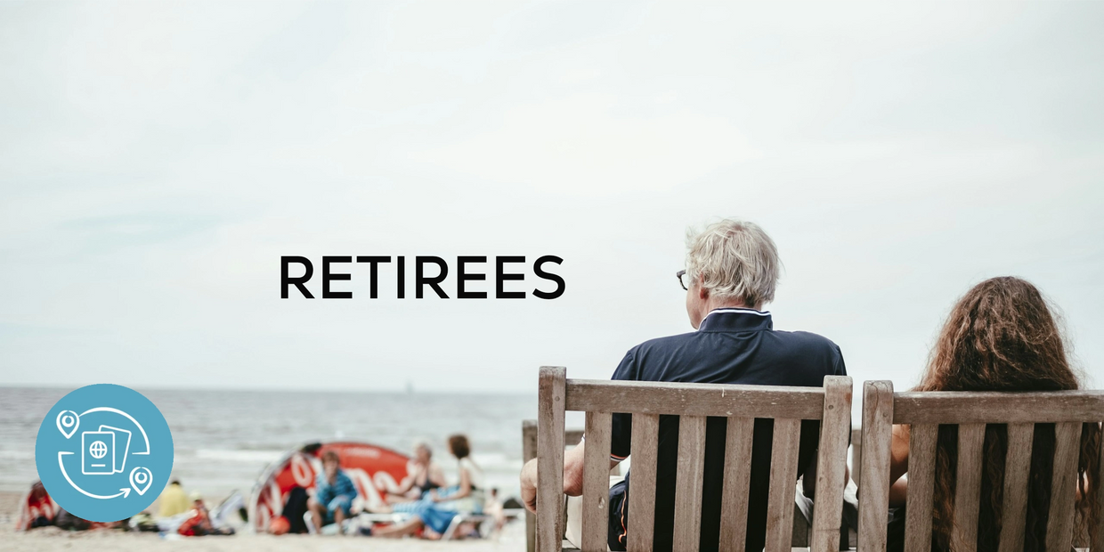 A man and woman sitting in wooden chairs on a beach with the word 'RETIREES'