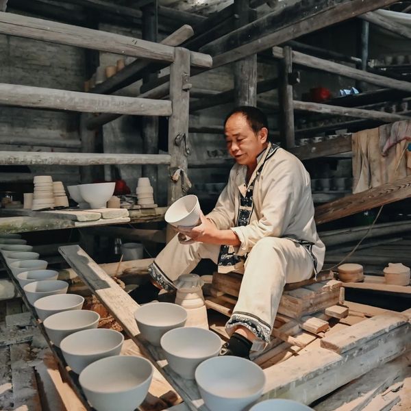 A craftsman inspects ceramic bowls in a traditional pottery workshop.