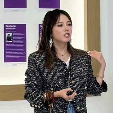 A woman speaking in front of a wall with informational plaques.