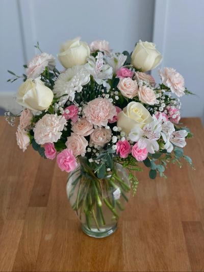 Elegant bouquet of white, pink, and cream flowers in a clear glass vase.
