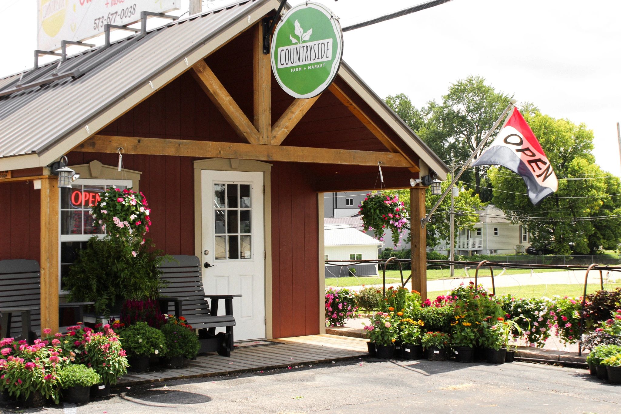 A farm market with flowers and open sign.