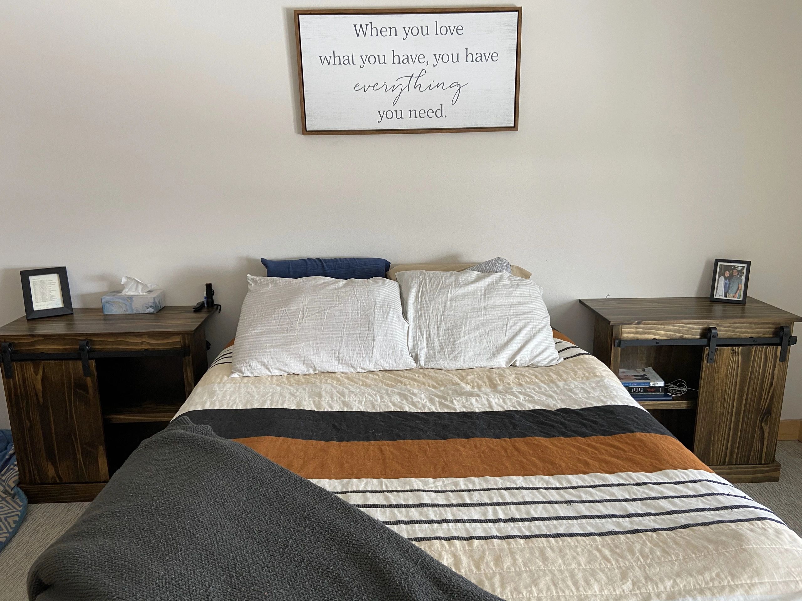 Bed with pillows and a wall sign above it.