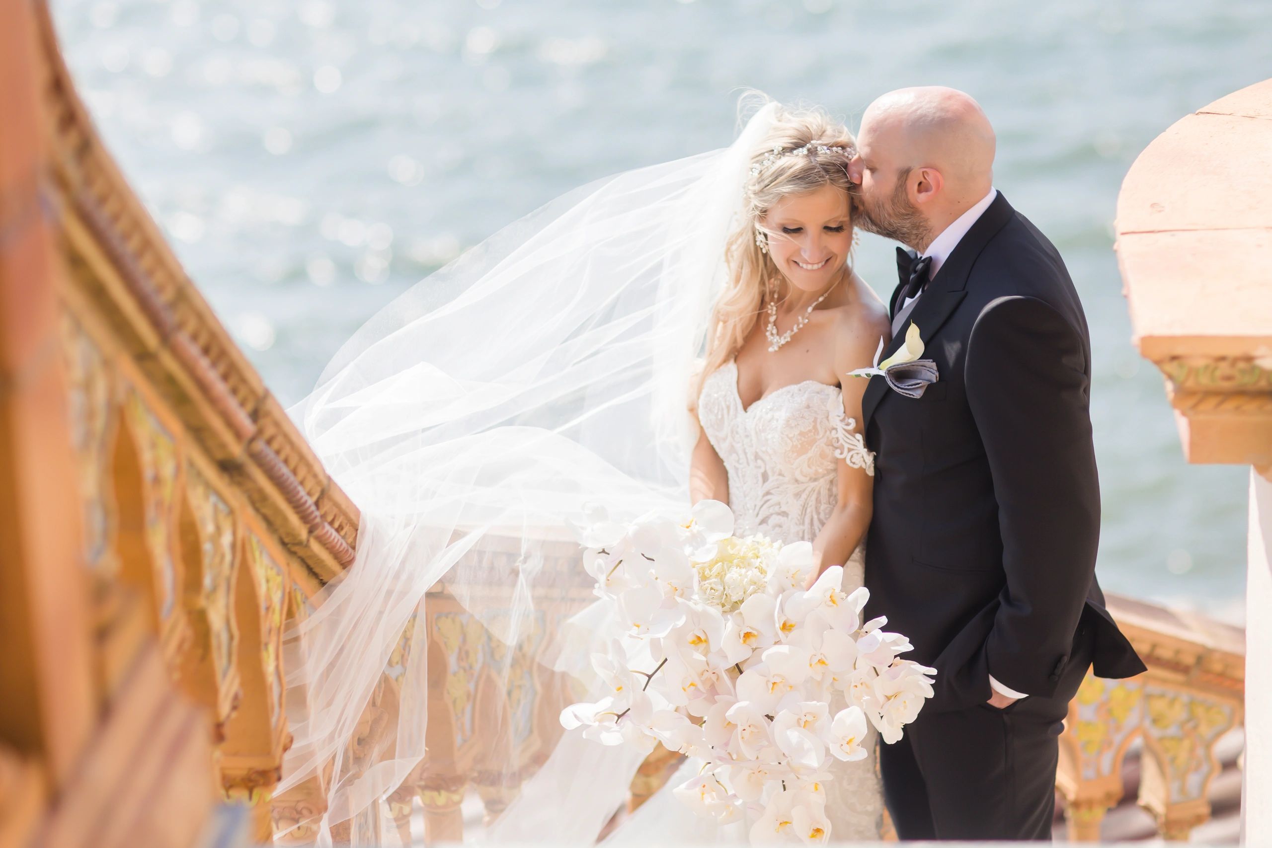 Bride and groom share a tender moment by the seaside on their wedding day.