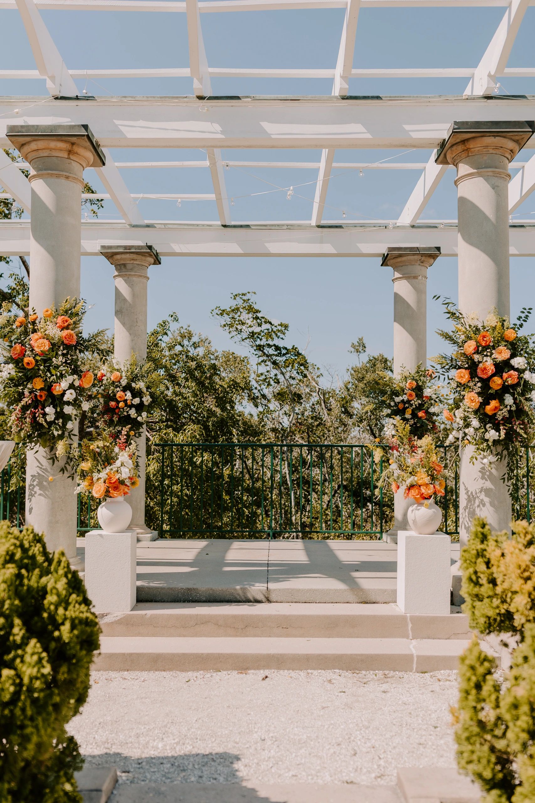 Outdoor wedding altar decorated with orange and white flowers under a pergola.
