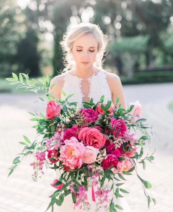 Bride holding a large bouquet of vibrant pink flowers and greenery.