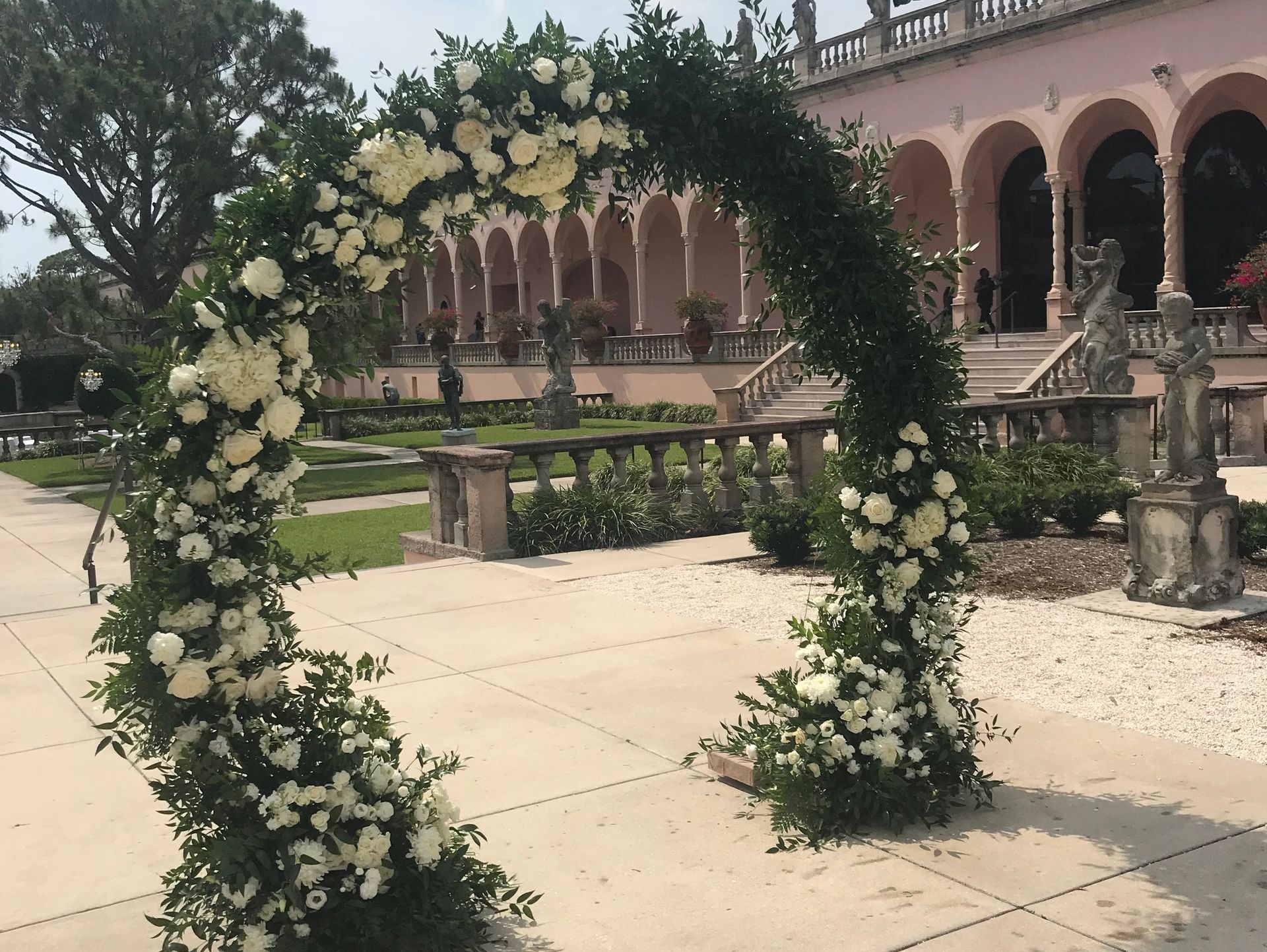 Floral arch decorated with white flowers and greenery in front of a historic building.