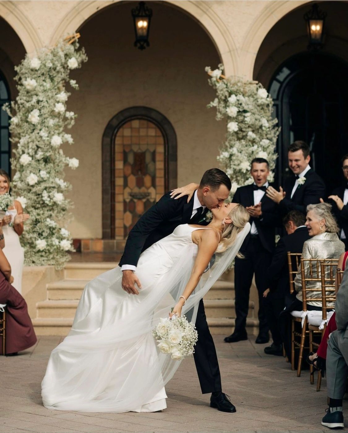 Bride and groom share a romantic kiss during wedding ceremony.