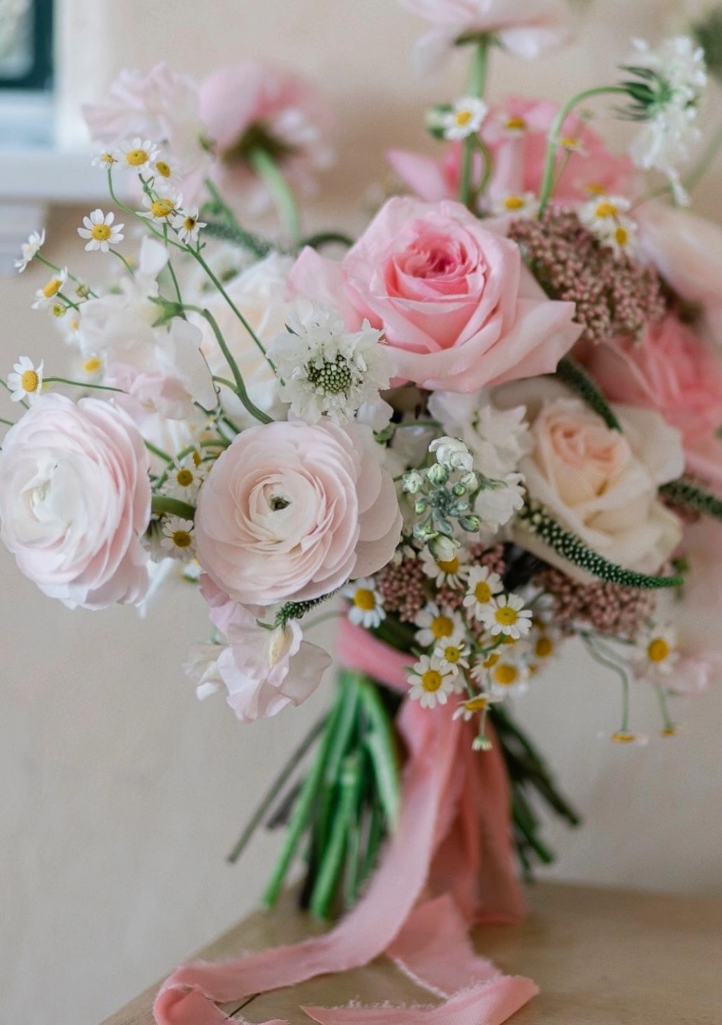 A delicate bouquet of pink and white flowers with a pink ribbon.