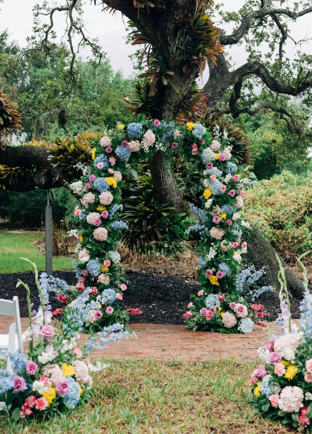 Floral archway decorated with colorful flowers for an outdoor event.