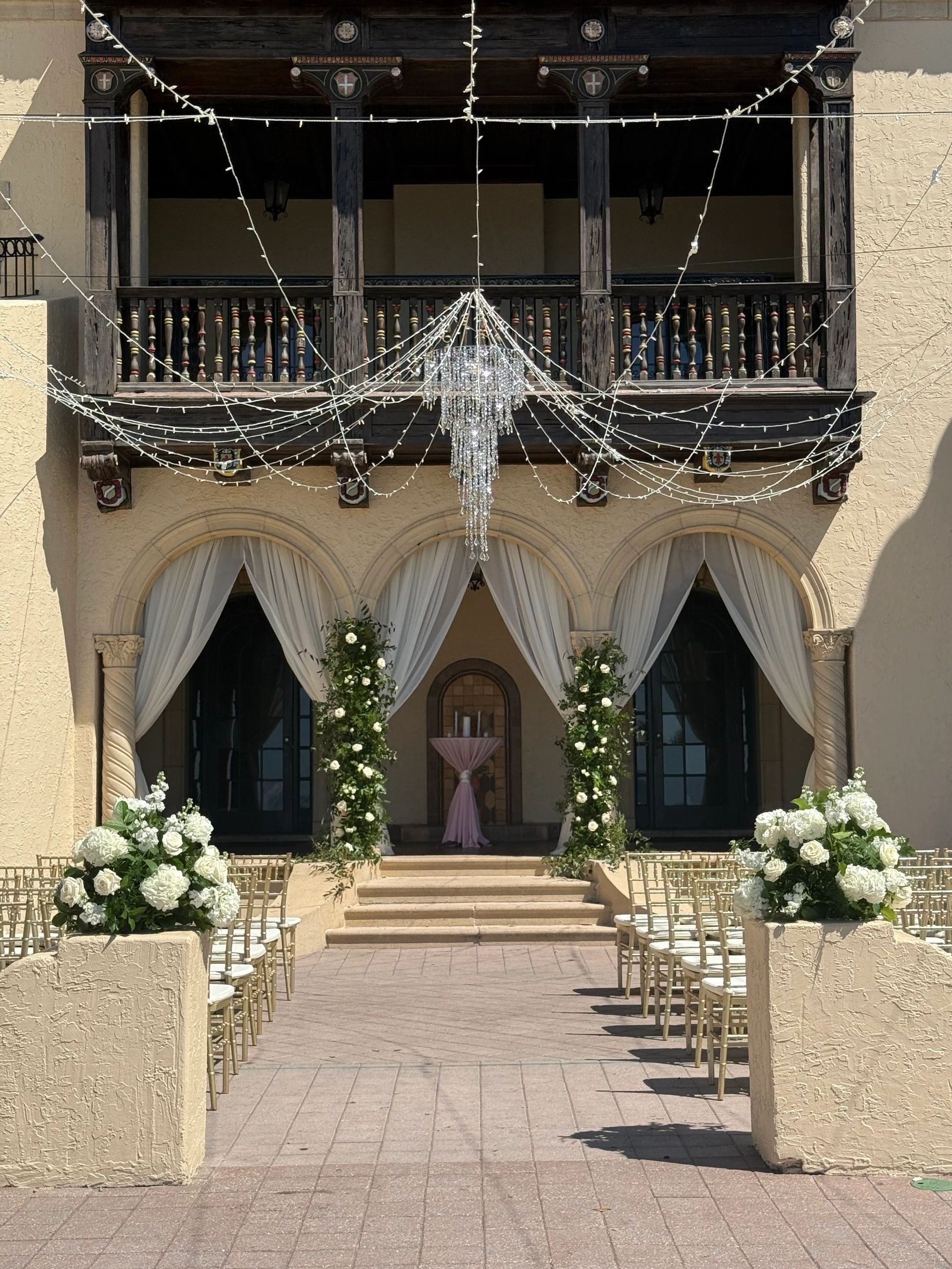 Elegant outdoor wedding setup with floral decorations and string lights.