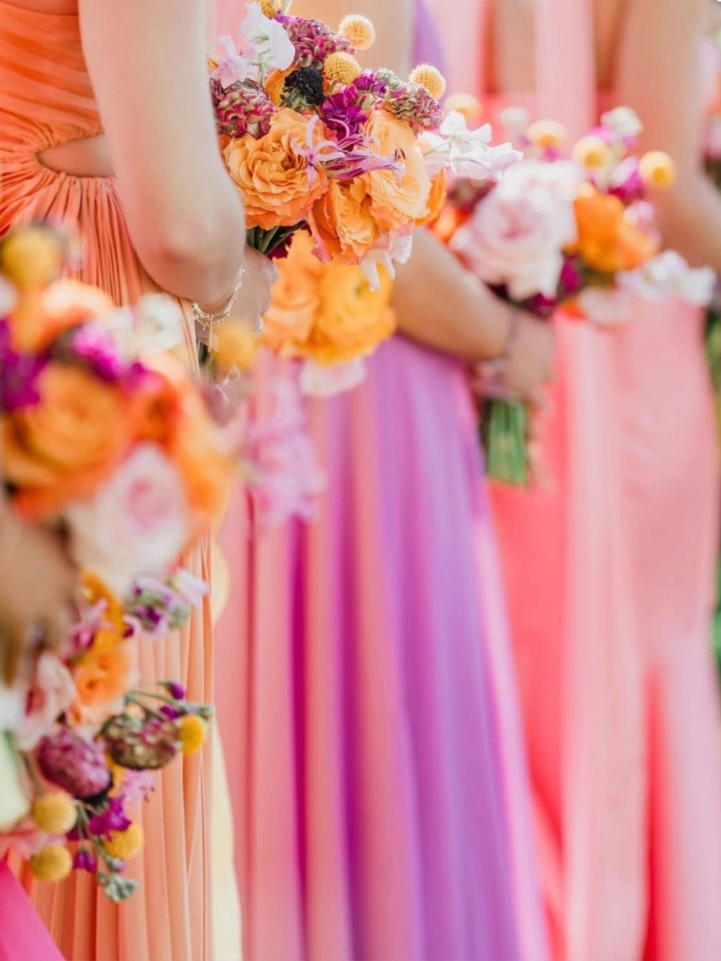 Bridesmaids holding vibrant bouquets in pastel dresses at a wedding.