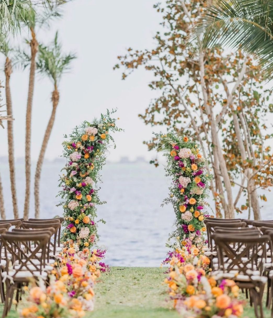 Outdoor wedding setup with floral arch by the water.