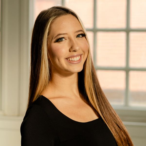 Smiling young woman with long hair in black top.