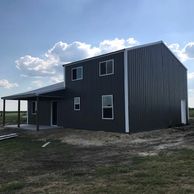 Texwin two story charcoal colored barndominium shell pole building installed on concrete.