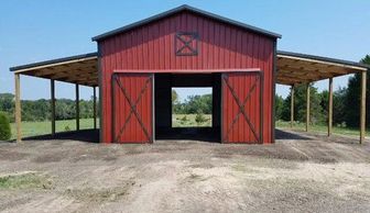 24x40x14 Red Texwin pole barn with 12x40x12 lean to sheds and 10x10 sliding doors.