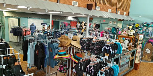 Inside a clothing and accessories store with hats and swimwear displayed.