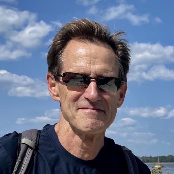 Man wearing sunglasses smiling outdoors.