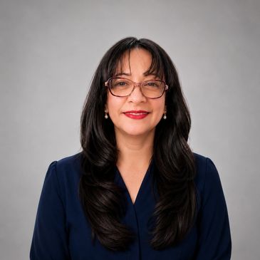 Smiling woman with long dark hair and glasses against a gray background.