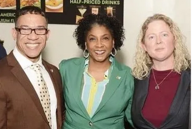 Three professionally dressed individuals smiling at a social event.