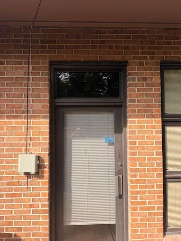 Door with blinds on red brick wall.