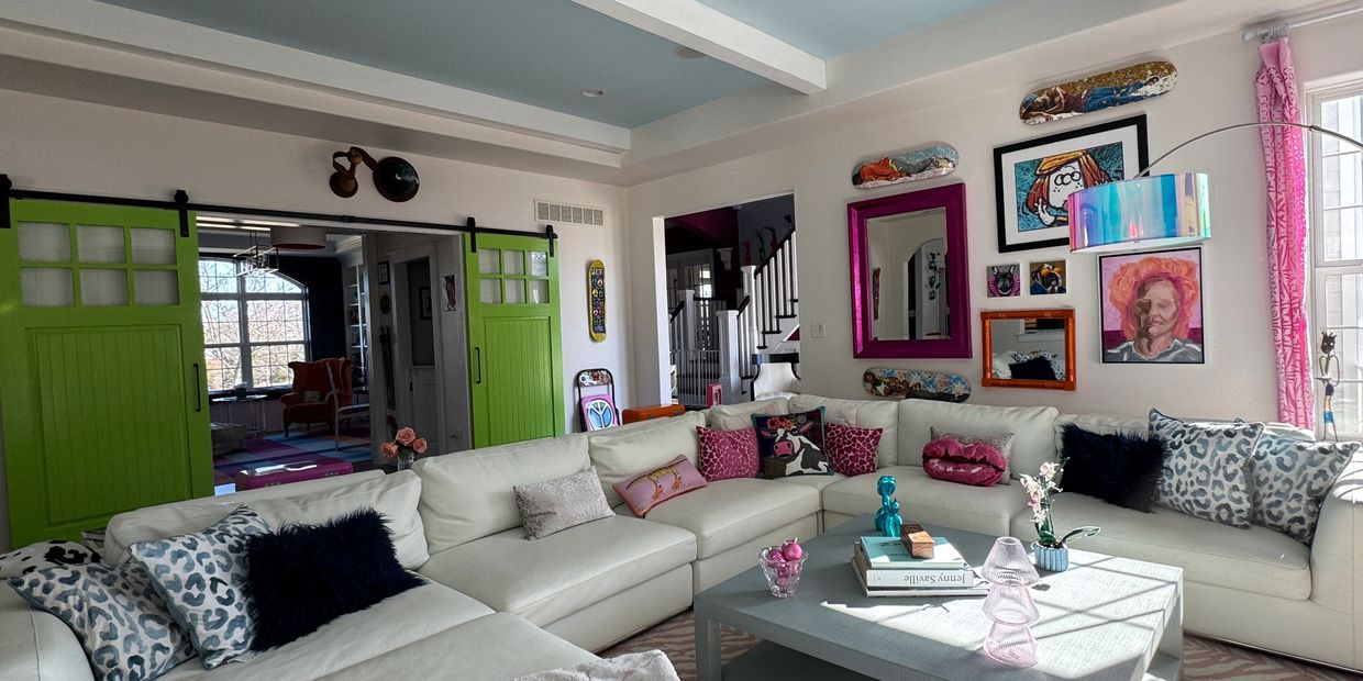 Bright living room with white sectional, green sliding doors, and colorful art decor.
