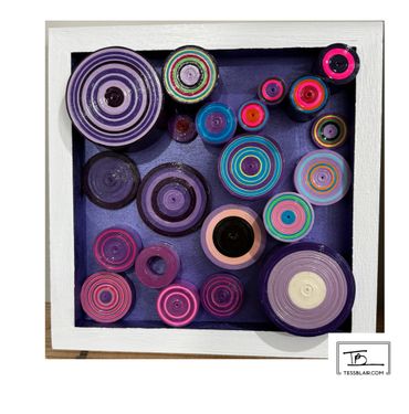 Colorful concentric circular art pieces displayed in a white frame with a dark purple background.