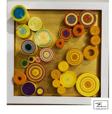 Colorful concentric circles art piece in a white frame with a gold background.