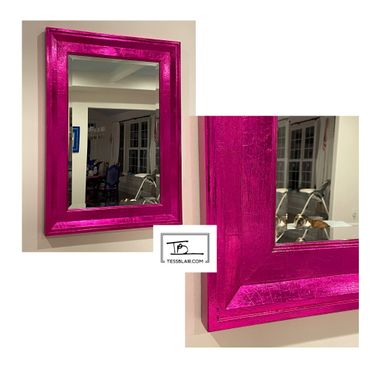 Vibrant pink metallic framed mirror reflecting a cozy room.