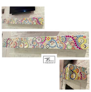 Colorful mosaic art decorating a fireplace mantel with intricate swirling patterns.