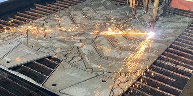 An image of a plasma cutting table at work cutting stainless steel.