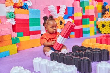 A baby plays with colorful foam blocks in a vibrant play area.