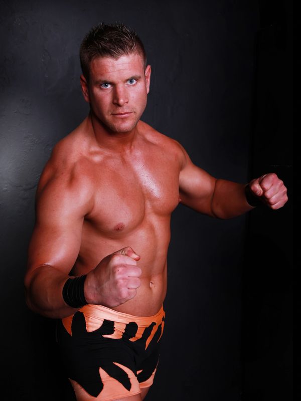 Muscular male wrestler posing with fists up in fighting stance.