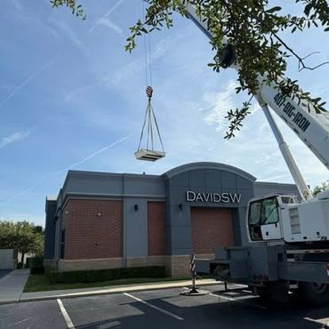 Crane lifting materials onto DAVIDSW building on a clear day.