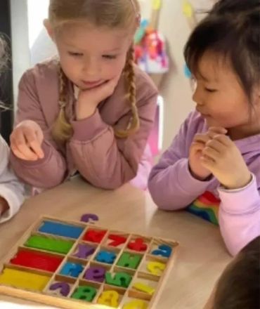 Children playing with colorful alphabet and number puzzle pieces.