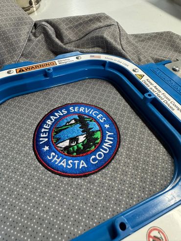 Embroidered Veterans Services patch for Shasta County inside an embroidery hoop.