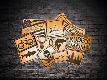 Rustic wooden coasters with various outdoor and patriotic designs on a brick wall background.