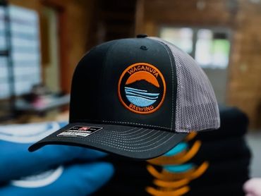 A black and gray trucker cap with a Waganguya Brewing logo embroidered on the front.
