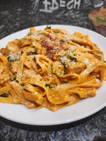 Plate of creamy pasta with tomato sauce and grated cheese.