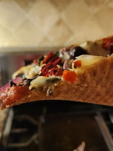 Close-up of a slice of veggie pizza with various toppings.