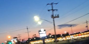 Blurred evening cityscape with streetlights and power lines at sunset.
