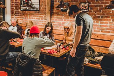A group of people learning how to shuck oysters at a table