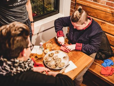Two ladies shaking oysters at a table in Maine