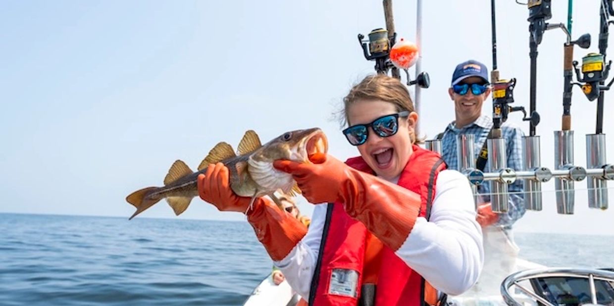 A teenage girl holding an Atlantic cod on a boat in Casco Bay Maine