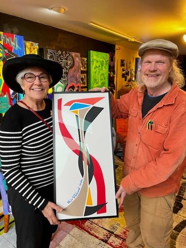 Artist milo holding Niki custom framed painting at Frameworks Northwest